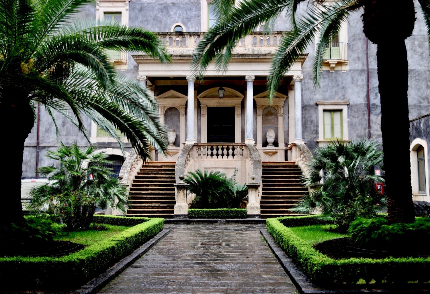 Binnentuin van een Italiaans palazzo met palmen en een dubbele bordestrap